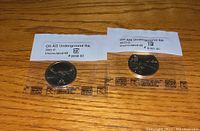 Two 2023-P and 2023-D Ohio Underground Railroad US $1 coins in sealed packaging with white mint labels on wooden surface.