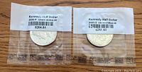 Two Kennedy half dollar coins sealed in protective plastic sleeves, each labeled with mint mark and uncirculated condition.