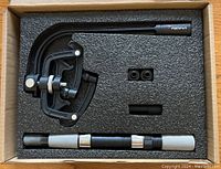 Fishing line spooler components neatly packed in foam-lined box: mounting arm, handle bar, two bushings, and small adapter piece.
