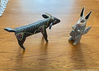 Two hand carved and painted wooden animal figures displayed on a wooden table