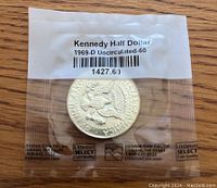 Front of the sealed 1969-D Kennedy Half Dollar coin showing label with grading and coin details.