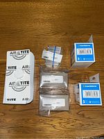 Photo shows multiple sealed boxes and loose Air-Tite branded packaging on wood surface, containing coin holders and supplies.