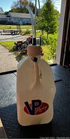 Front view of white plastic VP Racing fuel jug with clear plastic spout attached, showing VP Racing logo and handle.