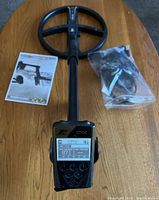 Assembled XP ORX detector with control unit screen, coil, manual, and bagged headphones on tabletop