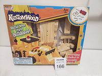 Box front showing KustomWood Build Your Own Bulldozer kit with window display of wooden parts, screwdriver and screws