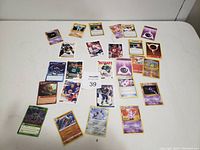 Photo shows 22 cards spread out on a flat white surface. Cards include Pokémon cards with characters and energy symbols, and hockey cards with players in uniforms.
