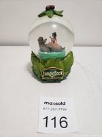 Full view of the Jungle Book snow globe showing Baloo and Mowgli inside and the leaf base with Jungle Book logo.
