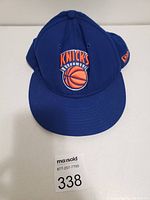 Blue New York Knicks basketball hat with embroidered team logo on front, displayed on white surface, maxsold label visible.