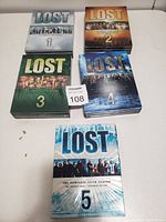 Five DVD box sets of Lost TV series seasons 1 to 5 arranged on a white surface.