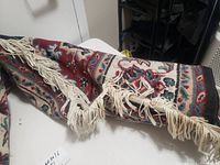 Photo of the rolled and laid out area rug showing multicolored pattern and white fringed edges.