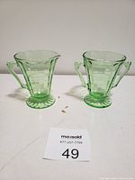Pair of vintage green glass sugar and milk bowls with ring pattern and flared bases, displayed on a white surface