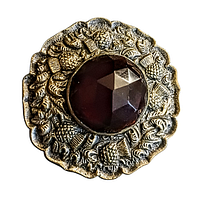Front view of an extra large antique Scottish silver plated brass kilt brooch with a faceted ruby colour glass stone and raised thistle motifs around the edge.