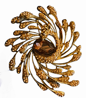 Close-up image of a large vintage signed figural peacock brooch with gold-tone metal, textured details, and a large brown faceted central stone. The brooch measures approximately 3 inches in diameter.