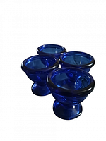 Four cobalt blue glass egg cups grouped together showing their shape and color from a side angle.