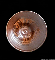 Top view of the Raku art pottery bowl showing the spiral pattern and earthy brown glaze inside with artistic markings.