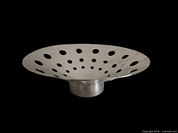 Side angle photo showing the curved stainless steel fruit platter with multiple round cutouts and cylindrical base.
