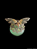 Front view of vintage frosted green glass perfume bottle with detailed enamel dragonfly lid.