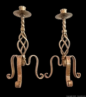 Two vintage gilded cast iron candleholders shown front-facing, detailing the twisted stem, lattice midsection, and curled three-legged base