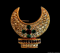 Front view of the crescent-shaped brooch pin showing gold tone and rhinestones with green and red accents