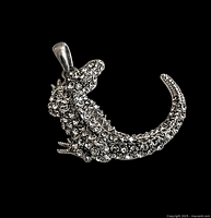 Front view of vintage rhinestone alligator pendant on a black background