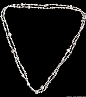 Full view of the long pearl necklace with mother of pearl accent beads laid out on flat black background for clear detail.