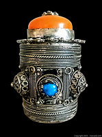 Front view of the cylindrical Tibetan coin silver container adorned with amber and turquoise cabochons and intricate filigree work.