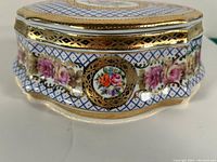 Front and side view of Limoges porcelain jewellery box showing floral hand-painted design and gold dipped rims with lattice pattern