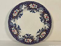 Full view of the plate showing patterned border in blue, pink, white and gold floral motifs