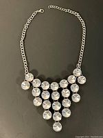 Full view of the silver-tone chain necklace with triangular pattern of clear faceted stones.