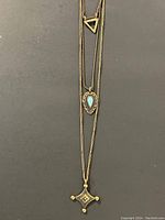 Full view of necklace showing three layered chains with distinct pendants on each.