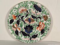 Top view of Old Coalport decorative plate showing detailed multicolored floral pattern with green leafy background.