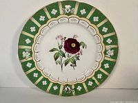 Full view of the antique plate showing green border with white flowers and a central purple floral design.