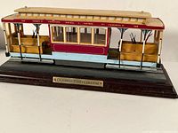 Side and angled view of the California cable car model showing its full length, wooden benches, and painted signage.