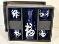 Photo shows the sake set in its original box, including carafe and four cups arranged in compartments.