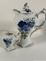 Front and side view of the Limoges porcelain coffee pot and matching creamer with blue rose floral design and gold trim