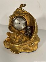 Full view of ornamental brass clock with clock face and figurine