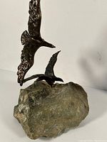 Side view of two bronze eagles in flight mounted on a natural stone base