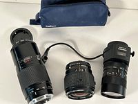 Photo showing three lenses and a Calor carrying case. Left lens Tamron 75-260mm with cable, middle Vivitar 28mm auto-focus, right third lens with manual aperture.