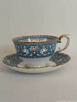 Side angle of Crown Staffordshire Ellesmere teacup and saucer showing teal floral and swan pattern with gold trim