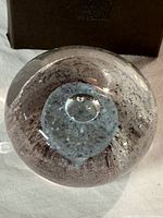 Top view showing the clear glass and blue-grey textured core with suspended bubbles inside the glass paperweight.
