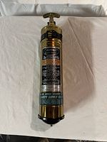 Front and full view of the vintage fire extinguisher on a white cloth background, showing overall appearance and condition.