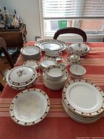 Overall view of the Bridgwood Conway dish set arranged on a table showing various plates, bowls, covered tureen, sugar bowl, and gravy boat with ornate trim and pattern.