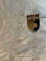 Eight Waterford crystal wine glasses arranged on white cloth with a care booklet.