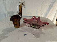Glass giraffe figurine and decorative bowl displayed together on cloth background.