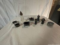 Full lot arrangement showing various small silver plated tableware pieces including shakers, condiment holders, and dishes