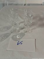 Four clear Waterford crystal aperitif glasses on white cloth, showing full set from an angled side top view.