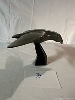 Side view of dark gray stone bird carving on angular black base