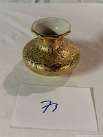 Front and top view of the small gold plated Kelley Ross 22K gold vase showing textured hammered surface and scalloped rim with white interior.