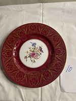 Full view of Royal Worcester bone china plate with red and gold detailed border and floral center design on white background.