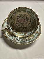 Top-down image showing floral design inside teacup and gold gilt decoration on rim and saucer.